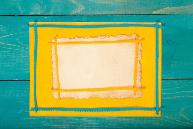 Желтая фетровая ткань на голубой деревянной поверхности. Задний план