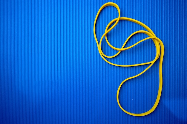 Yellow fitness rope on blue mat background