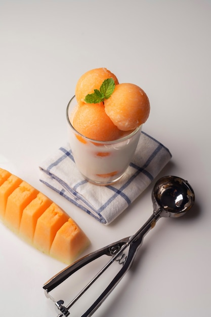 Foto il melone a polpa gialla è stato raccolto in una palla rotonda come il gelato messo in un bicchiere trasparente condito con latte fresco, dolce e delizioso.