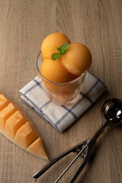 Il melone a polpa gialla è stato raccolto in una palla rotonda come il gelato messo in un bicchiere trasparente