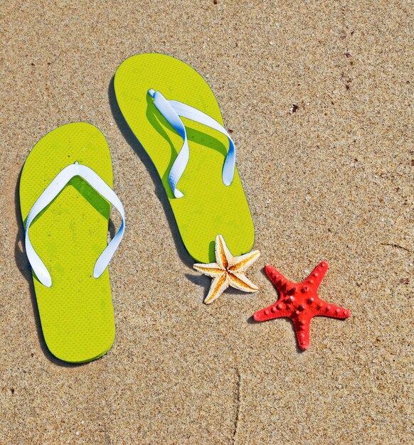 Photo yellow flip flops and starfish by the sea