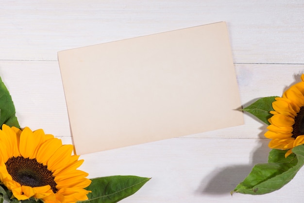 Yellow flowers and empty paper for your text on wooden background