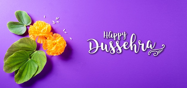 Yellow flowers green leaf and rice on purple pastel background Dussehra greeting