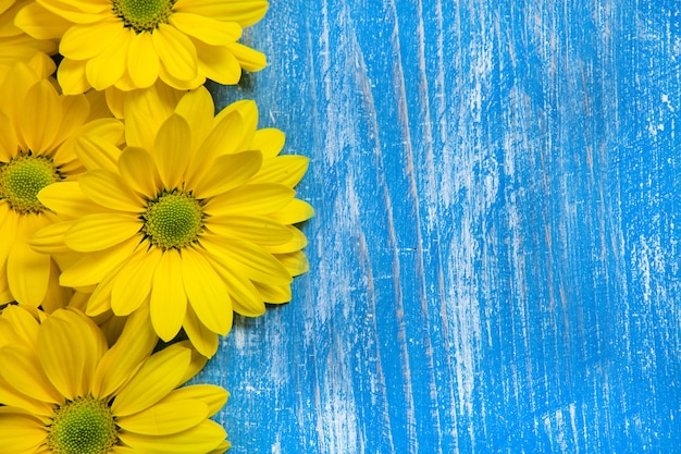 Photo yellow flowers over painted wooden background for text