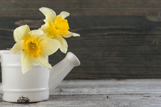 Yellow flowers in vase on wooden table. copyspace