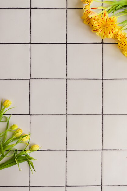 Yellow flowers on a white tile floor background