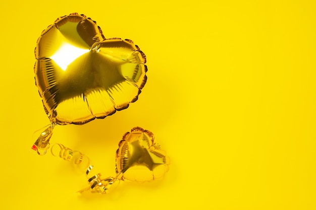 Yellow foil balloons in shape of heart on yellow