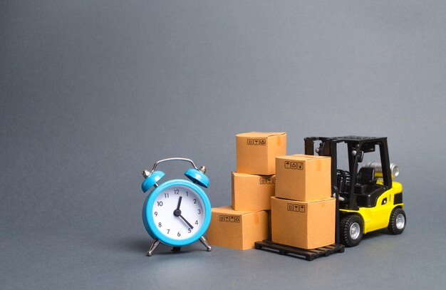 Photo yellow forklift truck with cardboard boxes and a blue alarm clock express delivery