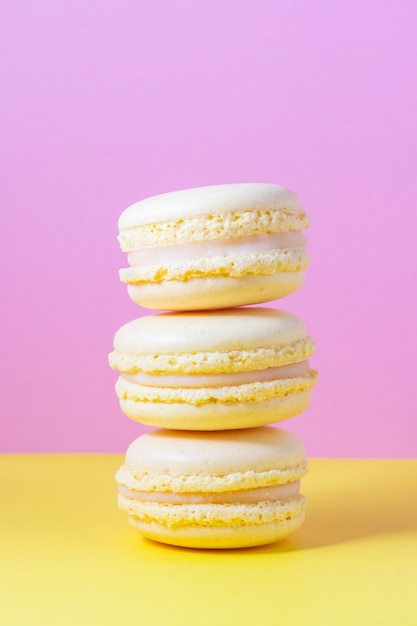 Foto pasticcini amaretti francesi gialli con crema al limone su giallo e rosa