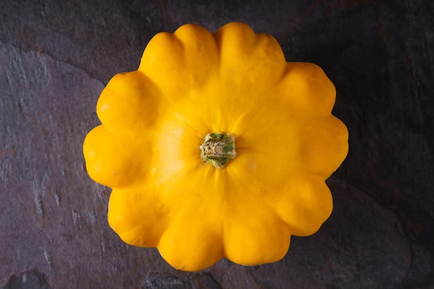 Yellow fresh squash patty pan on the dark stone background top view