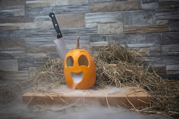 Yellow and funny halloween pumpkin with a knife in his head and smoke or steam from his mouth