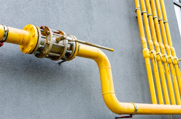 Фото Желтая газовая труба с краном идет вдоль фасада нового многоэтажного дома.