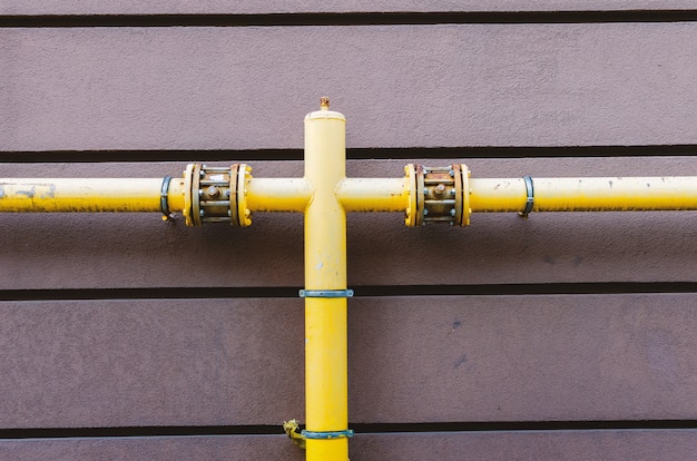 Yellow gas pipe with a crane goes along the facade of a new multi-storey building.