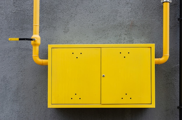 Yellow gas pipe with a crane goes along the facade of a new multi-storey building.