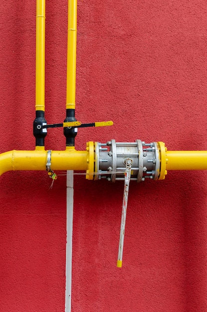 Yellow gas pipe with a crane goes along the facade of a new multi-storey building.