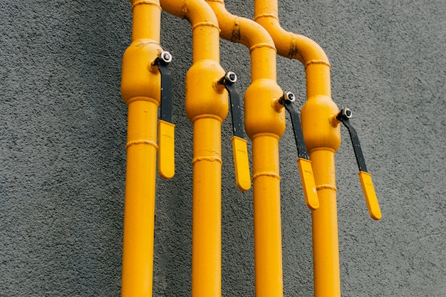 Photo yellow gas pipe with a crane goes along the facade of a new multi-storey building.