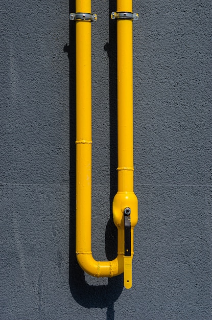 Yellow gas pipe with a vent on the facade of a multi-storey building. Natural gas for domestic household use, gas pipe line.