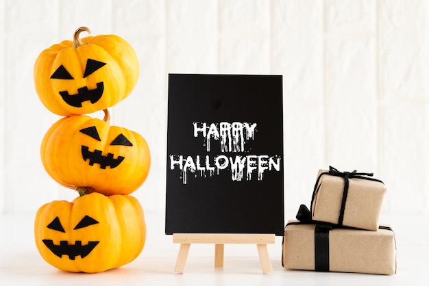 Yellow ghost pumpkin with gift box on white brick block background.