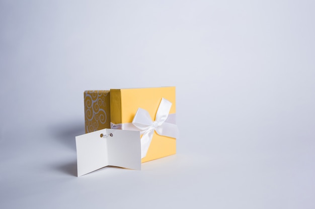 Yellow gift box with a white bow and an empty greeting card