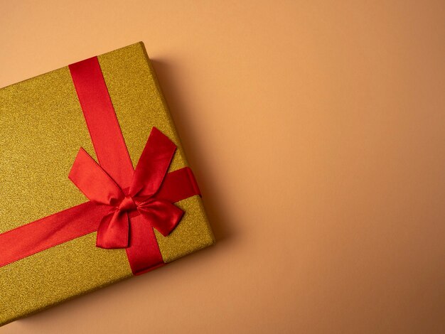 Yellow gift with a ribbon in the form of a butterfly knot lies on a nice orange background