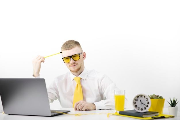 Yellow glasses manager looks intently at laptop, accent on yellow tie juice pot