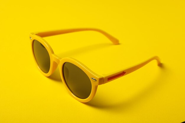 Yellow glasses with dark lenses on yellow background