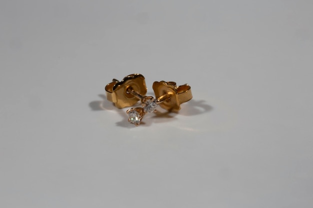 本物のダイヤモンドをあしらったイエローゴールドのイヤリング。シングルダイヤモンドの小さなカジュアルなイヤリング。白い背景の上の美しいイヤリング。レディースアクセサリー