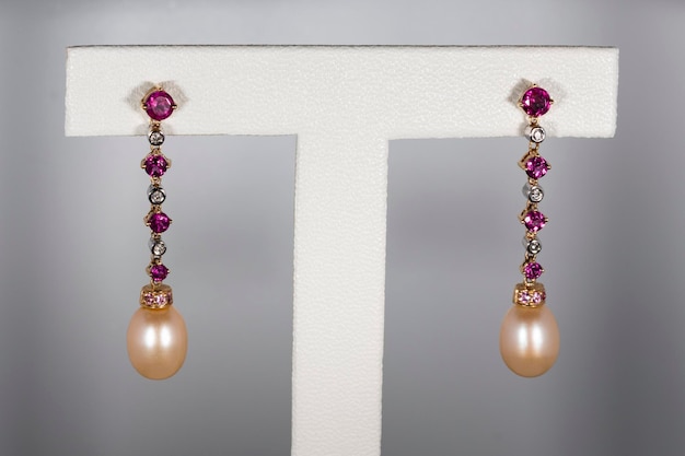 Yellow gold earrings with rubies diamonds and pearls on a white background