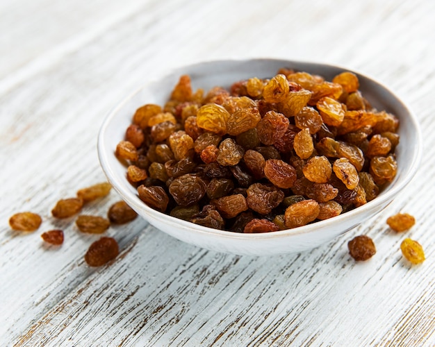 Yellow golden raisins on a white wooden background