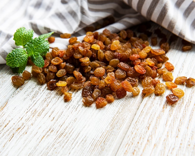 Yellow golden raisins on a white wooden surface