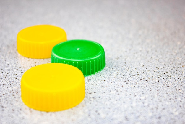 Yellow and green bright small plastic round lids on a green backgroundRound lids for closingPlastic bottle caps