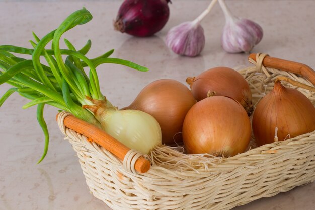 Yellow and green onions in a wicker basket