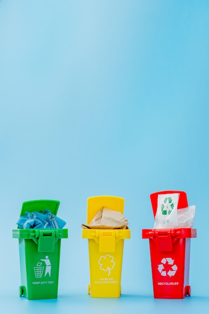 Yellow, green and red recycle bins with recycle symbol on blue background. keep city tidy, leaves the recycling symbol. nature protection concept