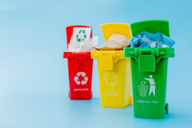 Yellow, green and red recycle bins with recycle symbol on blue