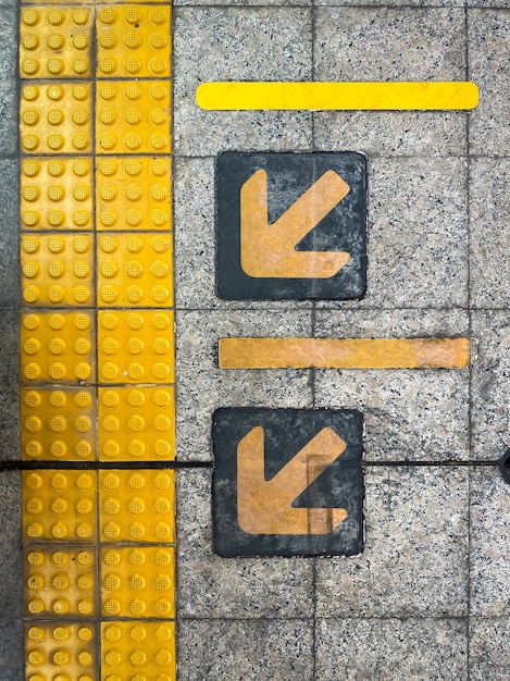 Yellow guiding block brick floor pattern with arrow sign in the train station