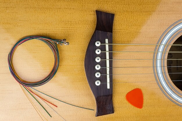 Photo yellow guitar pick tucked into gold acoustic guitar strings