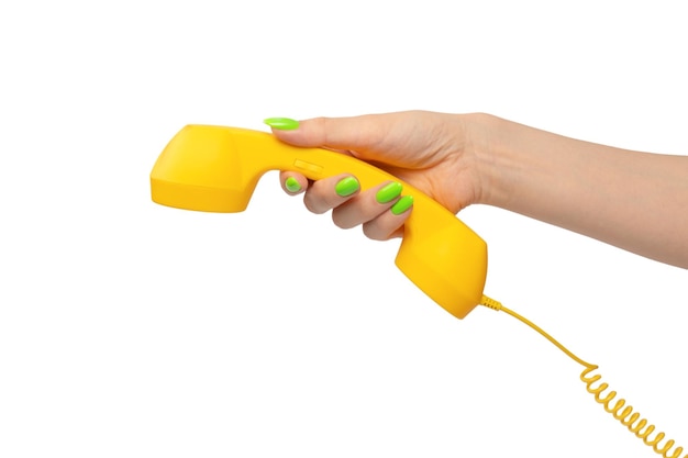 Yellow handset in woman hand with green nails isolated on a white background