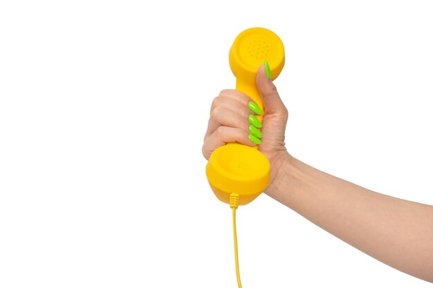 Photo yellow handset in woman hand with green nails isolated on a white background