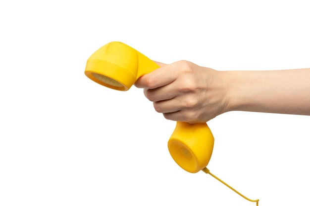 Yellow handset in woman hand with green nails isolated on a white background