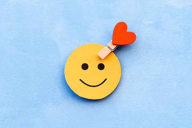 Yellow happy smiley face on a blue background and a red heart as the emotion selection The concept of mood selection and customer feedback Copy space business and emotions