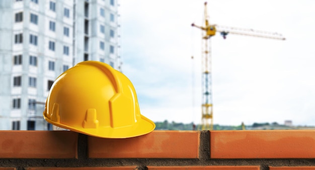 Yellow hard hat on brickwall, construction concept