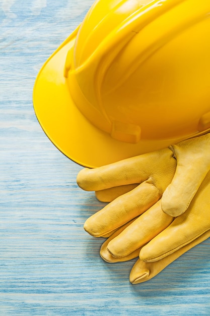 Yellow hard hat safety gloves on wooden board construction concept