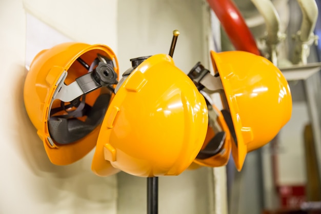 Yellow hard hat safety wear helmet hanging on coat rack at construction site