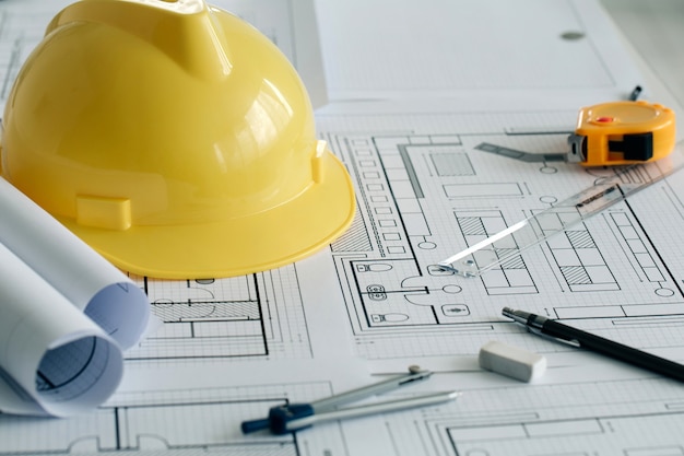 yellow hard safety helmet hat and the blueprint pen ruler protractor and tape measure on  table