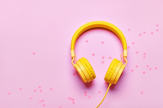 Yellow headphones and confetti on pink background Minimal Music concept flat lay copy space