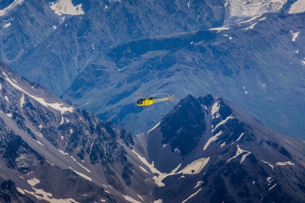 A yellow helicopter on a background of mountains