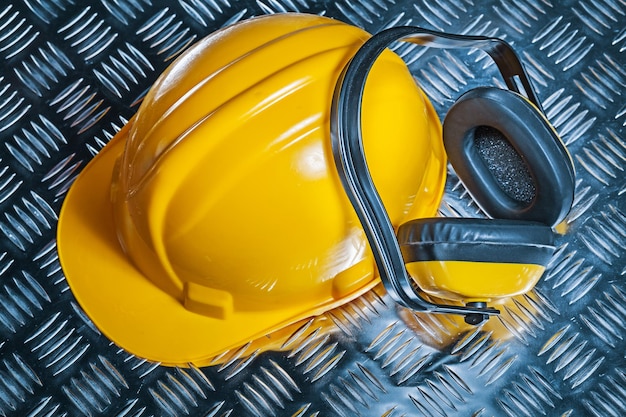 Yellow helmet and  earphones on corrugated sheet of metal