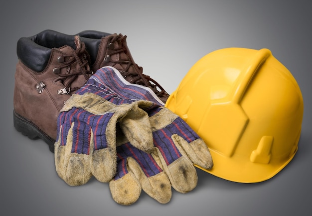 Casco giallo con stivali e guanti su fondo di legno