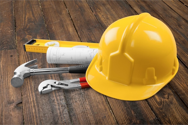 Yellow helmet with equipment on wooden background