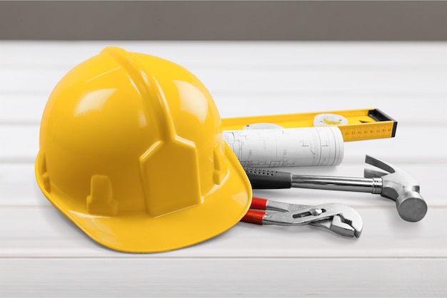 Yellow helmet with equipment on wooden table background